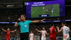 Referee signaling a VAR offside review at the 2026 World Cup with stadium screen showing the decision